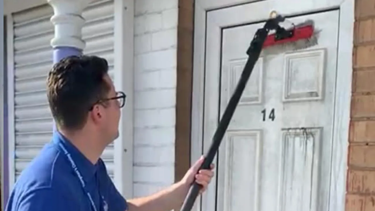 Tom cleaning the glass and white frame of a customer's front door with a pure-water brush